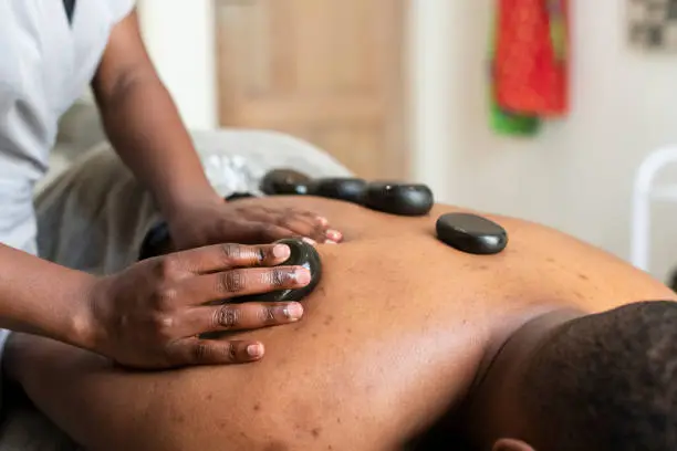 Lastone therapy performed by masseuse on clients back
